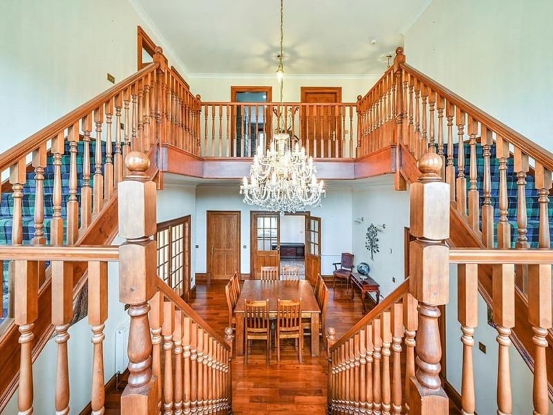 The grand reception hall featuring a chandelier and staircase leads onto a living room, kitchen, office, two bedrooms, plus an annexed living room and kitchen.