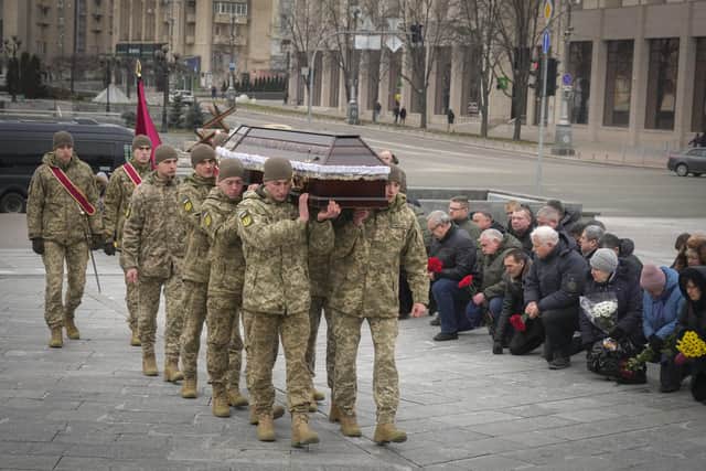 People stand kneeling as the Ukrainian servicemen carry the coffin of their comrade Oleh Yurchenko killed in a battlefield with Russian forces in the Donetsk region during a commemoration ceremony in Independence Square in Kyiv. Picture: AP Photo/Efrem Lukatsky