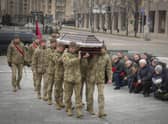 People stand kneeling as the Ukrainian servicemen carry the coffin of their comrade Oleh Yurchenko killed in a battlefield with Russian forces in the Donetsk region during a commemoration ceremony in Independence Square in Kyiv. Picture: AP Photo/Efrem Lukatsky