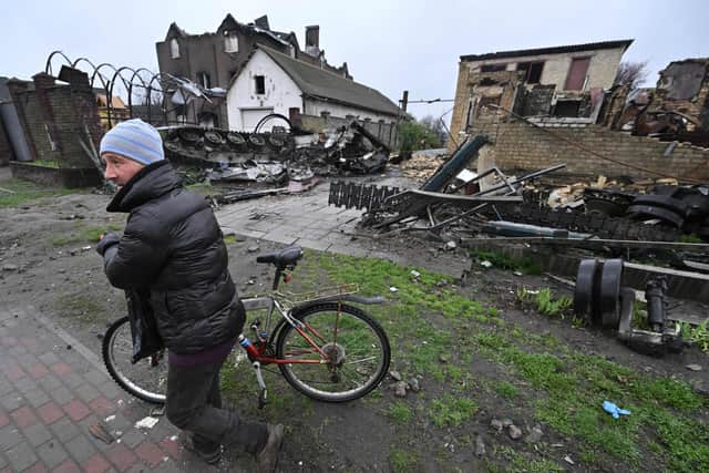 A man pushes his bicycle past a destroyed Russian armoured personnel carrier in the village of Gostomel, close to Kyiv. Picture: Genya Savilov/AFP/Getty