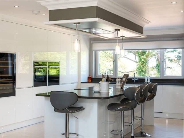 Kitchen with integrated appliances, including two ovens, wine fridge and seamless stone worktops.