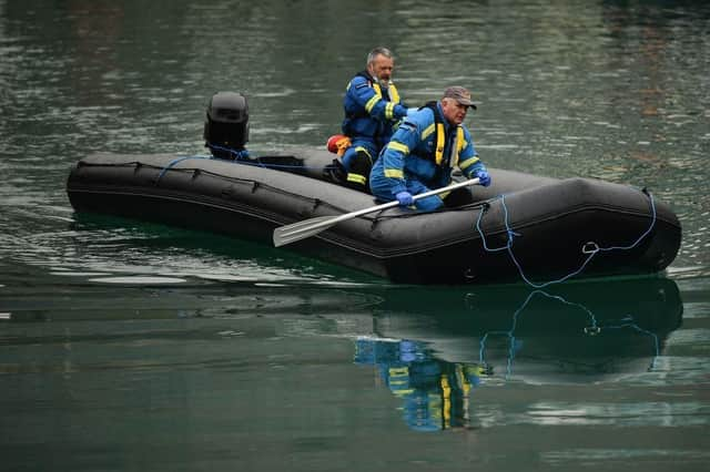 UK coastguards paddle on a dinghy inflatable boat used by migrants to cross the English Channel, as they bring it into Marina in Dover, southeast England, last month.