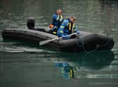 UK coastguards paddle on a dinghy inflatable boat used by migrants to cross the English Channel, as they bring it into Marina in Dover, southeast England, last month.