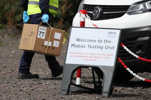 Staff from the Scottish Ambulance Service carry boxes of test kits from a van at a Covid Mobile Testing Unit in a car park in the Pollokshields area of Glasgow.