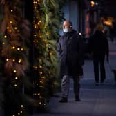 A man wearing a face mask passes an illuminated Christmas window display. Picture: Dominic Lipinski/PA Wire