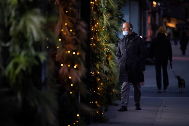 A man wearing a face mask passes an illuminated Christmas window display. Picture: Dominic Lipinski/PA Wire