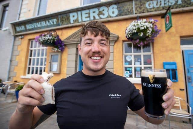 Jordan Leckey holding a celebrity jam sandwich and pint of Guinness outside Pier 36 at Donaghadee Harbour in Northern Ireland after his record swim (Liam McBurney/PA)