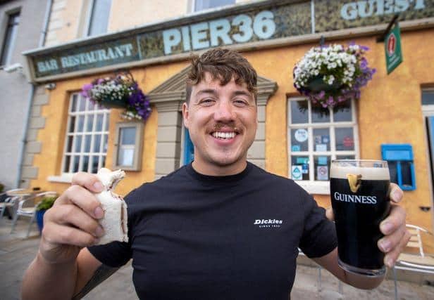 Jordan Leckey holding a celebrity jam sandwich and pint of Guinness outside Pier 36 at Donaghadee Harbour in Northern Ireland after his record swim (Liam McBurney/PA)