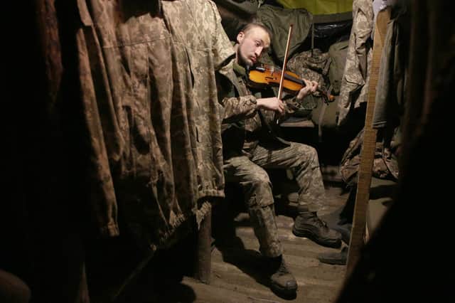 A Ukrainian soldier plays the violin in a dugout on the frontline with Russia-backed separatists, not far from Gorlivka, in the Donetsk region, in December (Picture: Anatolii Stepanov/AFP via Getty Images)
