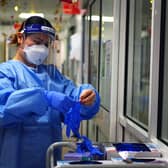 A nurse puts on PPE in a ward during the height of the pandemic