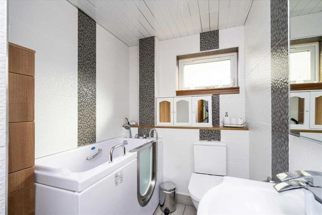 Bathroom with modern white three-piece suite including jacuzzi bath with low level access.