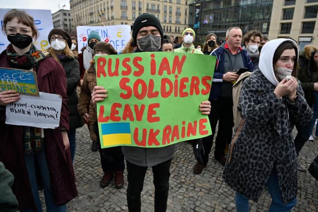 A man holds a placard reading "Russian Soldiers Leave Ukraine" as demonstrators protest against Russia's invasion of Ukraine in front of the Brandenburg Gate in Berlin. Photo:JOHN MACDOUGALL/AFP via Getty Images.