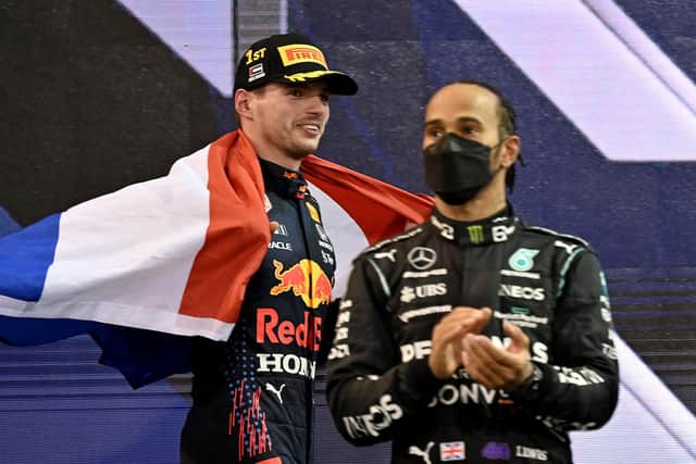 2021 FIA Formula One World Champion Red Bull's Dutch driver Max Verstappen walks past second-placed Mercedes' British driver Lewis Hamilton.