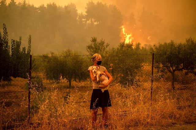A woman repurposes a Covid face mask amid the smoke from forest fires near the village of Pefki on Evia island in Greece last year (Picture: Angelos Tzortzinis/AFP via Getty Images)