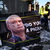 A photo of RMT general secretary Mick Lynch is seen on a poster as a group of workers stand on a picket line outside a train depot. Picture: Leon Neal/Getty Images