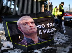 A photo of RMT general secretary Mick Lynch is seen on a poster as a group of workers stand on a picket line outside a train depot. Picture: Leon Neal/Getty Images