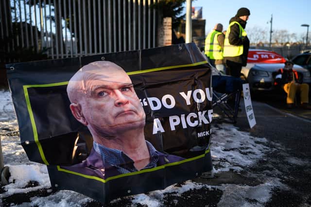 A photo of RMT general secretary Mick Lynch is seen on a poster as a group of workers stand on a picket line outside a train depot. Picture: Leon Neal/Getty Images