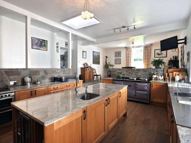 The kitchen itself was only recently installed and includes an Aga, various integrated appliances, and a central island with a granite worktop.
