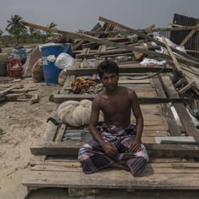 Fisherman Md. Mizan Molla from Bangladesh sits in front the wreckage of the house he shares with his parents, wife and brothers after a storm struck