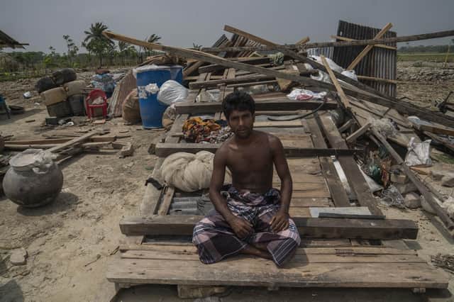 Fisherman Md. Mizan Molla from Bangladesh sits in front the wreckage of the house he shares with his parents, wife and brothers after a storm struck