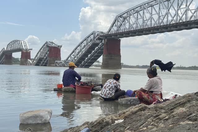 Members of a rural community wash clothes in front of the collapsed Ava Bridge in Sagaing following the earthquake in Myanmar. Picture: CARE Myanmar/DEC