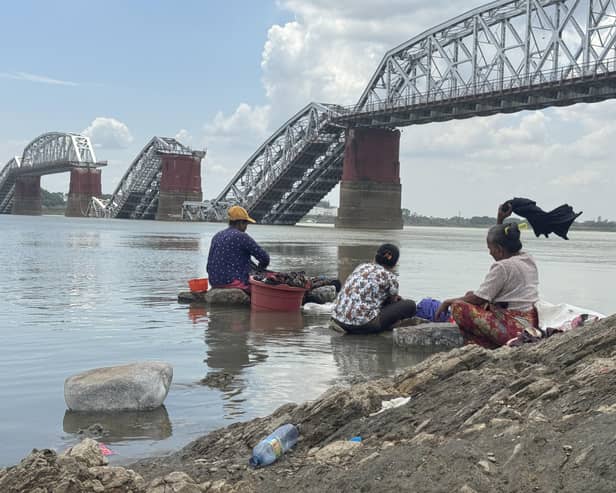 Members of a rural community wash clothes in front of the collapsed Ava Bridge in Sagaing following the earthquake in Myanmar. Picture: CARE Myanmar/DEC