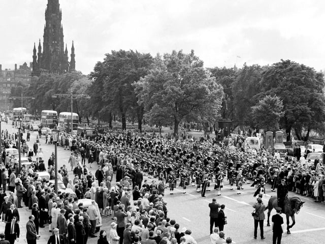 Crowds gather to watch the Edinburgh City Police Pipe Band as it marches along Princes Street during the Edinburgh International Festival in August 1966.