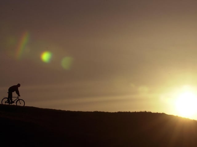 A cyclist makes his way along the top of Salisbury Crags at sunset.