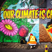 Street artists Ciaran Globel and Conzo Throb paint a mural designed by Colin Li, 14, on a wall opposite the COP26 climate summit venue in Glasgow in 2021 (Picture: Andy Buchanan/AFP via Getty Images)