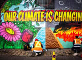 Street artists Ciaran Globel and Conzo Throb paint a mural designed by Colin Li, 14, on a wall opposite the COP26 climate summit venue in Glasgow in 2021 (Picture: Andy Buchanan/AFP via Getty Images)