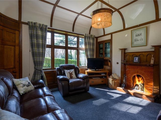 The family room has a coved ceiling, carved fireplace, built in wall cabinets, and an intriguing curved door that leads via a porch to the garden.