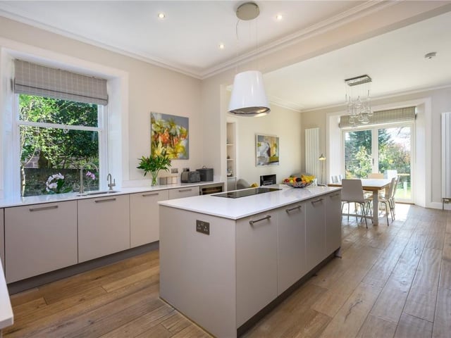 Fitted kitchen with integrated appliances, large central island, induction hob, boiling water tap, wine fridge, waist level ovens, and an engineered oak floor.