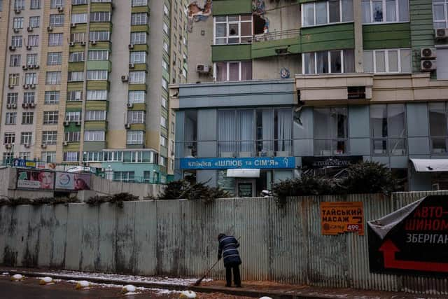 A woman clears the rubble of a damaged building in Kyiv.