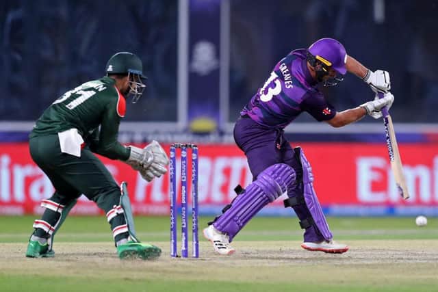 Scotland's Chris Greaves (R) plays a shot as Bangladesh's wicketkeeper Nurul Hasan watches during the ICC mens Twenty20 World Cup cricket match between Bangladesh and Scotland at the Oman Cricket Academy Ground in Muscat on October 17, 2021. (Photo by HAITHAM AL-SHUKAIRI/AFP via Getty Images)