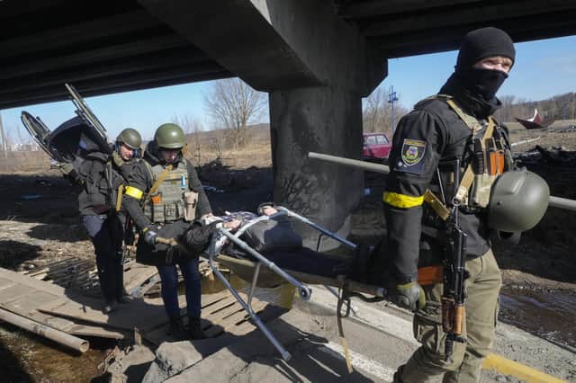 Ukrainians soldiers pass an improvised path under a destroyed bridge as they evacuate an elderly resident in Irpin, 16 miles north-west of Kyiv, yesterday. (Picture: AP/Efrem Lukatsky)