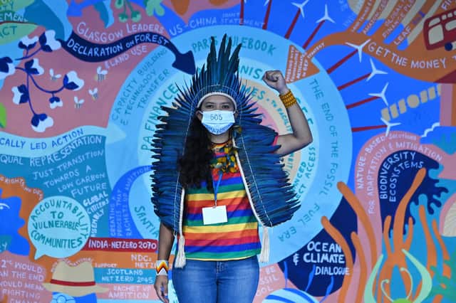 Climate activist, Jaciara Beatrix Sousa stands in front of a climate change mural at COP26 in Glasgow on Friday