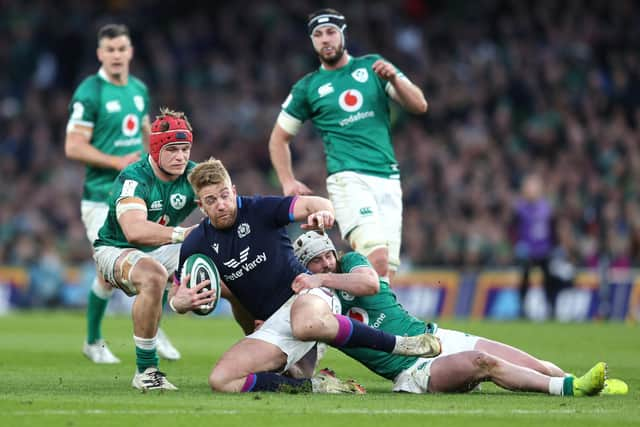 Kyle Steyn of Scotland is tackled by Josh Van der Flier and Mack Hansen of Ireland.