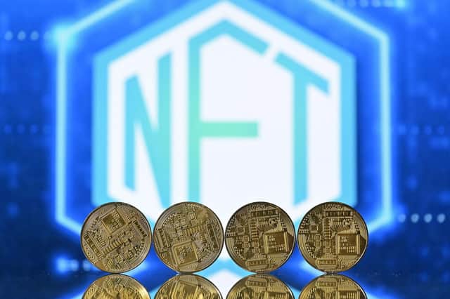 Gold-plated souvenir cryptocurrency coins arranged by a screen displaying an NFT (non-fungible token) logo (Picture: Justin Tallis/AFP via Getty Images)