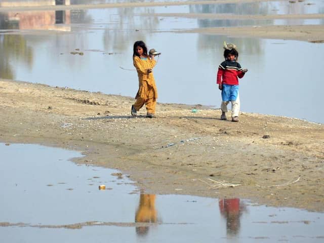 Internally displaced girls walk beside the flood waters near a makeshift camp in the flood-hit area of Dera Allah Yar in Jaffarabad district of Balochistan province, months after Pakistan was hit with devastating flooding. Picture: AFP via Getty Images