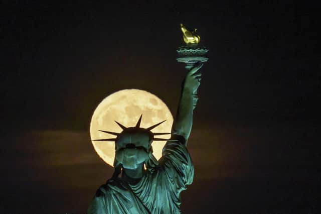 A Strawberry Supermoon surge em frente à Estátua da Liberdade em Nova York, na terça-feira, 14 de junho de 2022. (AP Photo/J. David Ake)
