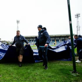 Dundee groundsmen remove the pitch covers ahead of the postponement of the match against Rangers. (Photo by Ewan Bootman / SNS Group)