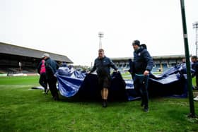 Dundee groundsmen remove the pitch covers ahead of the postponement of the match against Rangers. (Photo by Ewan Bootman / SNS Group)