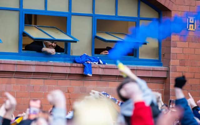 Rangers manager Steven Gerrard looks out of the dressing room window to greet supporters celebrating after the 3-0 win over St Mirren which effectively secured the Premiership title. (Photo by Craig Williamson / SNS Group)