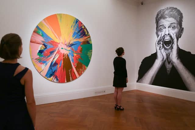 A Sotheby's employee studies a picture of David Bowie beside one of the artworks he owned ahead his collection going under the hammer in 2016
