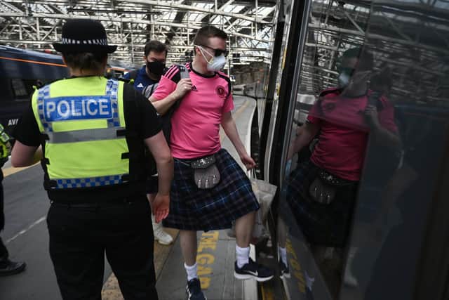Scotland fans wearing masks board a train at Glasgow's Central Station as they head to London (Picture: John Devlin)