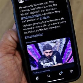 A phone displays a Tweet about the hanging by Iranian authorities of Mohsen Shekari. Picture: AFP via Getty Images