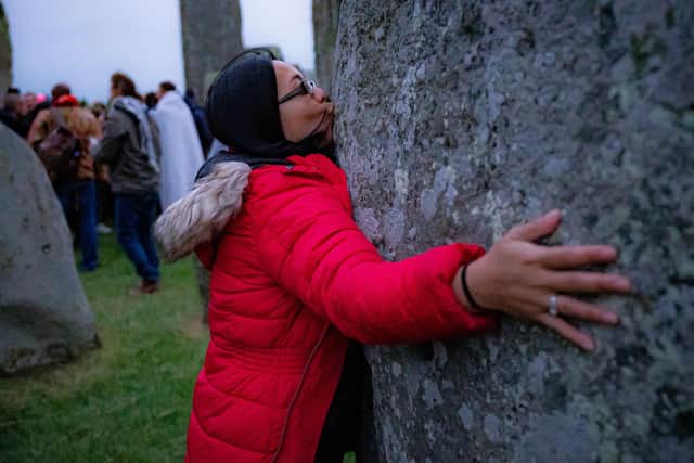 A woman kisses a stone during Summer Solstice at Stonehenge.