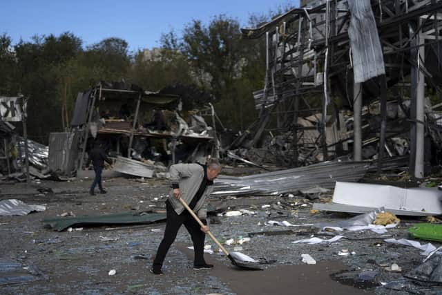 An employee cleans the debris at the remains of a car shop that was destroyed after a Russian attack in Zaporizhzhia, Ukraine, Tuesday, Oct. 11, 2022. (AP Photo/Leo Correa)