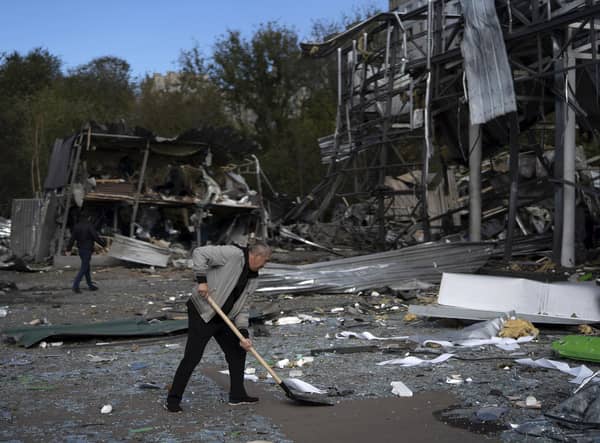 An employee cleans the debris at the remains of a car shop that was destroyed after a Russian attack in Zaporizhzhia, Ukraine, Tuesday, Oct. 11, 2022. (AP Photo/Leo Correa)