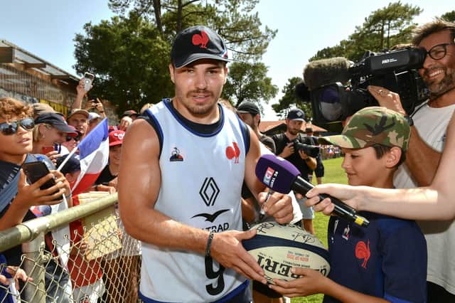 France's scrum-half Antoine Dupont signs a rugby ball for a young fan after a training session at the Bourret stadium, in Capbreton, southwestern France. He will captain Les Bleus against Scotland.  (Photo by GAIZKA IROZ/AFP via Getty Images)
